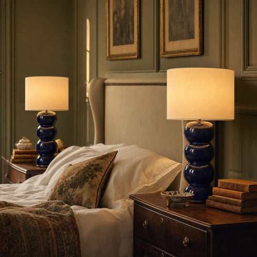 Pair of Cosmati table lamps on bedside tables in a country-house bedroom — sage panelled walls, linen bedding, gilt-framed paintings, antique walnut chests