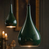 Detail of two Halcombe teardrop shades in glossy Studio Green enamel, candlelit interior beyond, showing the curved silhouette and surface finish