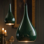 Detail of two Halcombe teardrop shades in glossy Studio Green enamel, candlelit interior beyond, showing the curved silhouette and surface finish