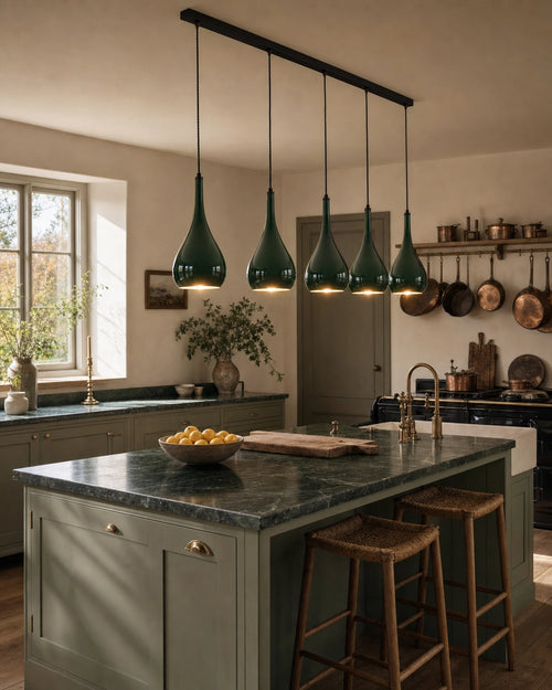 Halcombe five-light linear pendant above a kitchen island with green marble counter and sage Shaker cabinetry, mid-morning natural daylight