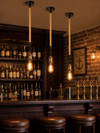 Three Rotherhithe hemp rope pendant lights hanging above a dark wood bar