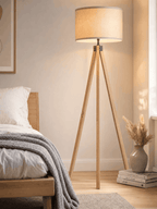 Highgate wood tripod floor lamp casting soft light in a minimal, serene bedroom corner