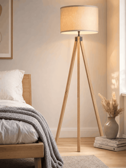 Highgate wood tripod floor lamp casting soft light in a minimal, serene bedroom corner