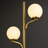 Close-up detail of Kensington gold metal arms and frosted glass globe shades