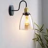 Whitechapel Amber Glass Gooseneck Wall Sconce by ZYVORAN illuminated in a cosy living room setting, showcasing its warm amber