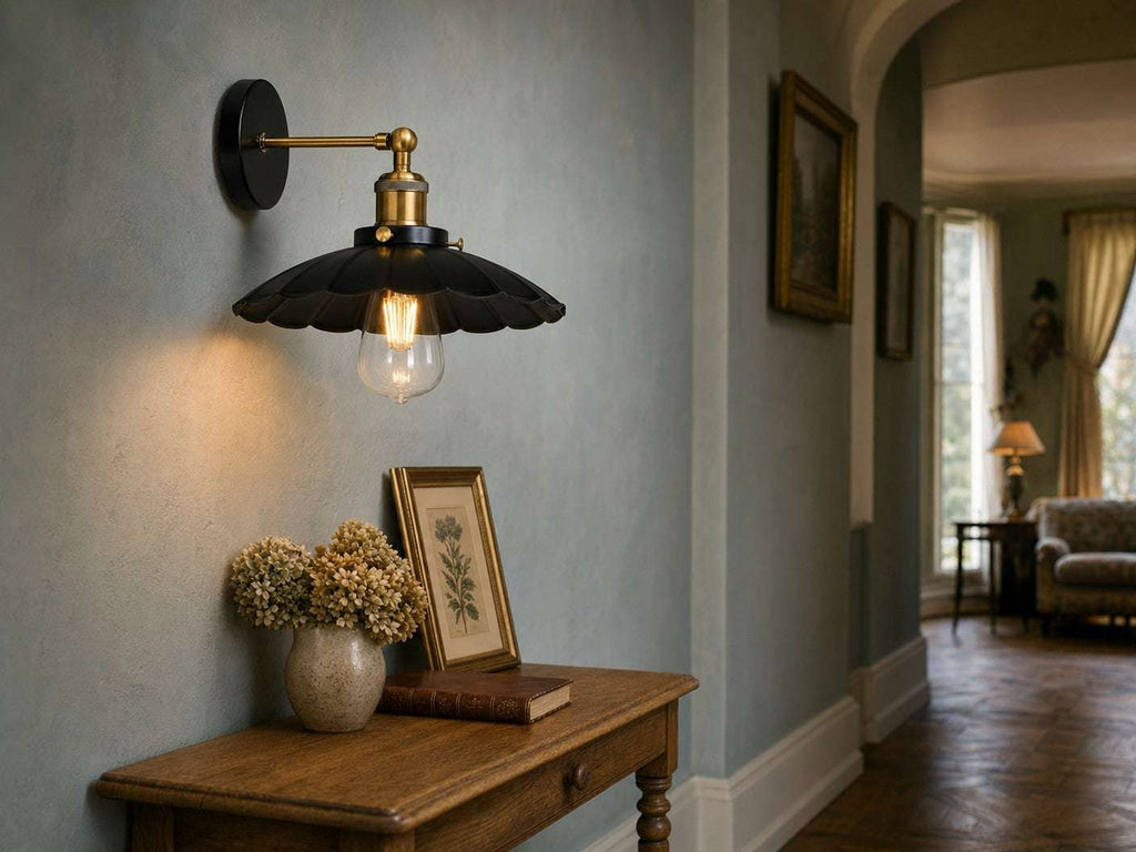 Marlow scalloped dome wall sconce in black metal with polished brass arm above an oak console table in an English country hotel hallway with duck-egg blue walls and oak parquet floor