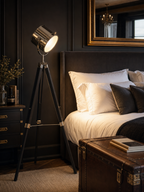 Pinewood searchlight tripod floor lamp as bedside reading light in a luxurious master bedroom with dark panelled walls and brass mirror