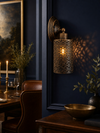 Spitalfields perforated copper wall sconce mounted on navy blue wall in an elegant dining room with leather chairs