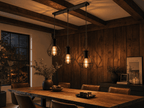 Whitechapel geometric cage pendants illuminating rustic dining table with leather chairs