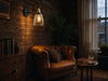 Whitechapel amber-glass gooseneck wall sconce mounted on an exposed-brick wall above a vintage tan leather chesterfield armchair in an evening reading nook