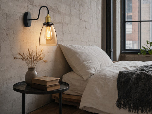 Stepney amber-glass gooseneck wall sconce mounted on a chalky off-white limewashed brick wall beside a low platform bed in a Victorian-warehouse-conversion bedroom